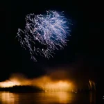 Blue-fireworks-illuminating-night-sky-over-water