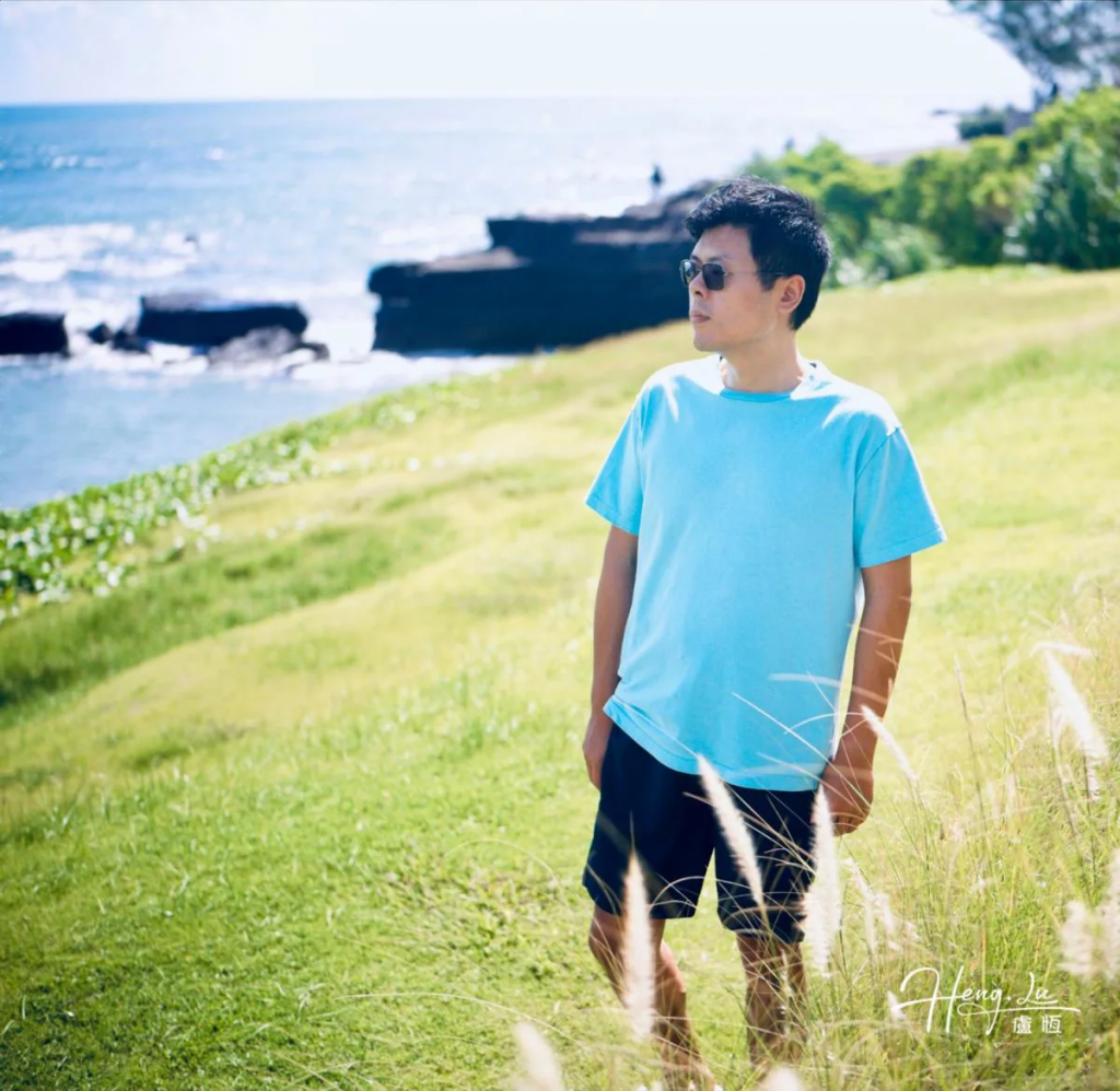 Luheng-in-blue-tee-standing-on-grassy-seaside