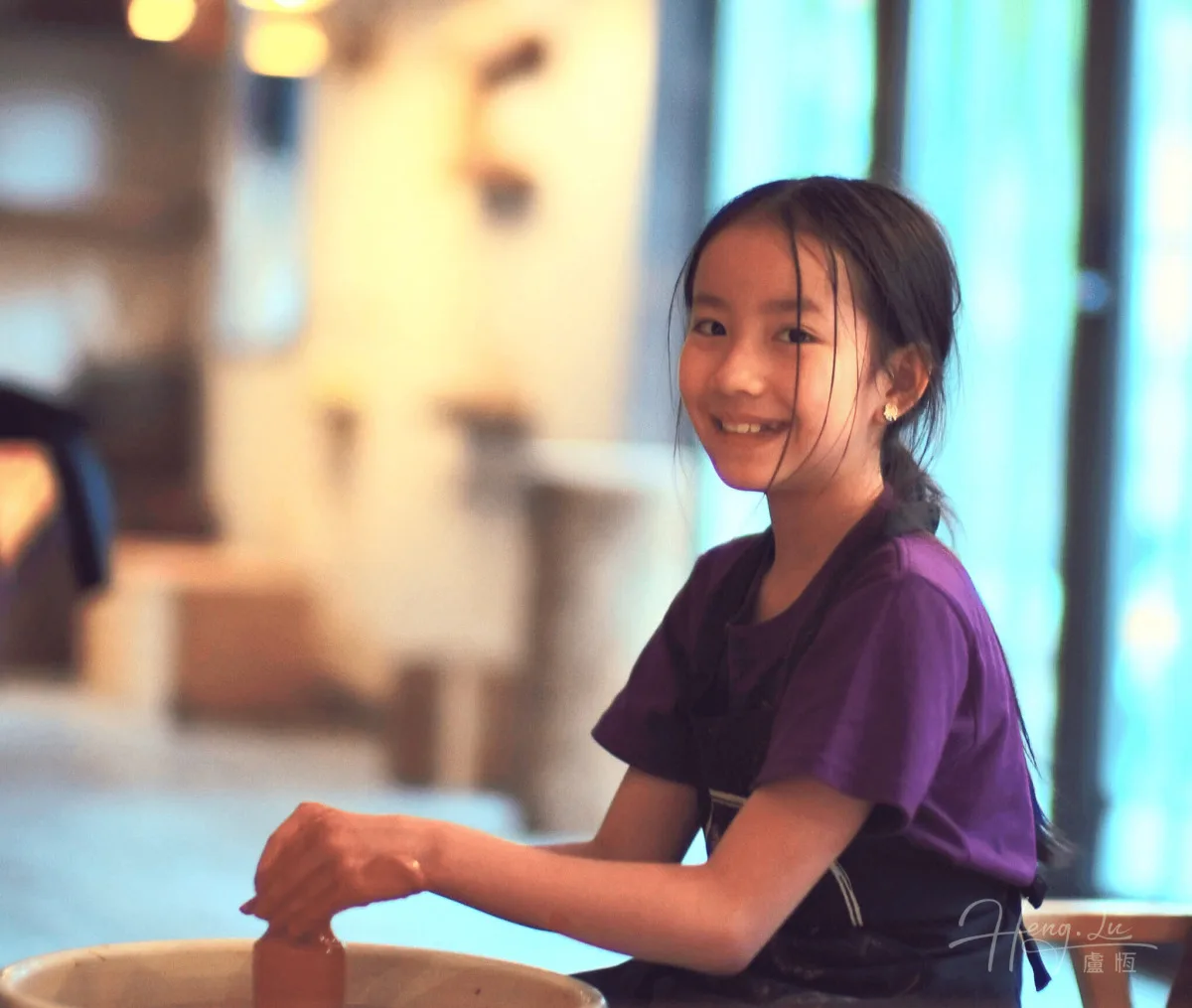 Girl-smiling-while-shaping-clay-in-pottery-class