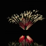Golden-and-red-fireworks-reflect-brightly-over-calm-water