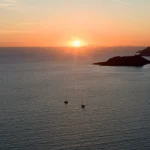 Sunset-over-sea-with-two-sailboats