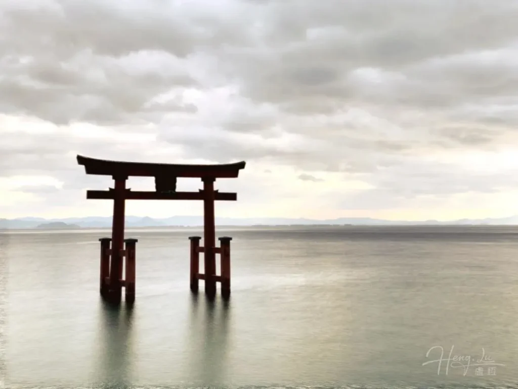 Torii-gate-standing-in-calm-water-under-cloudy-sky