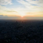 Sunset Over Dense Cityscape with Silhouetted Buildings and Golden Sky sunset-over-dense-cityscape-with-silhouetted-buildings