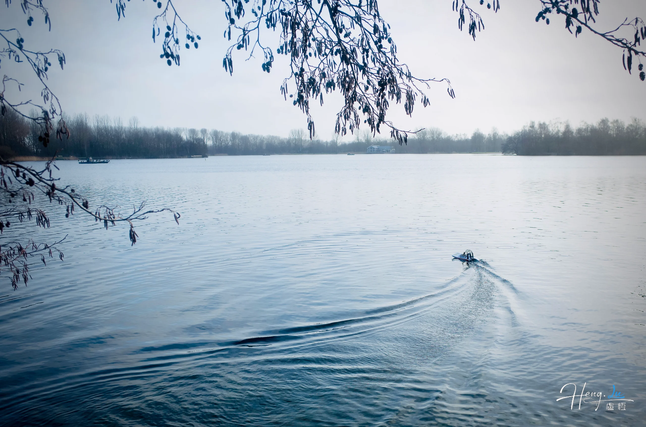 Small boat on calm lake with bare trees small-boat