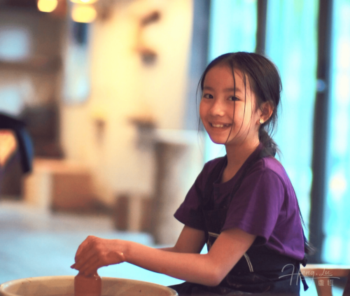 Girl-smiling-while-shaping-clay-in-pottery-class